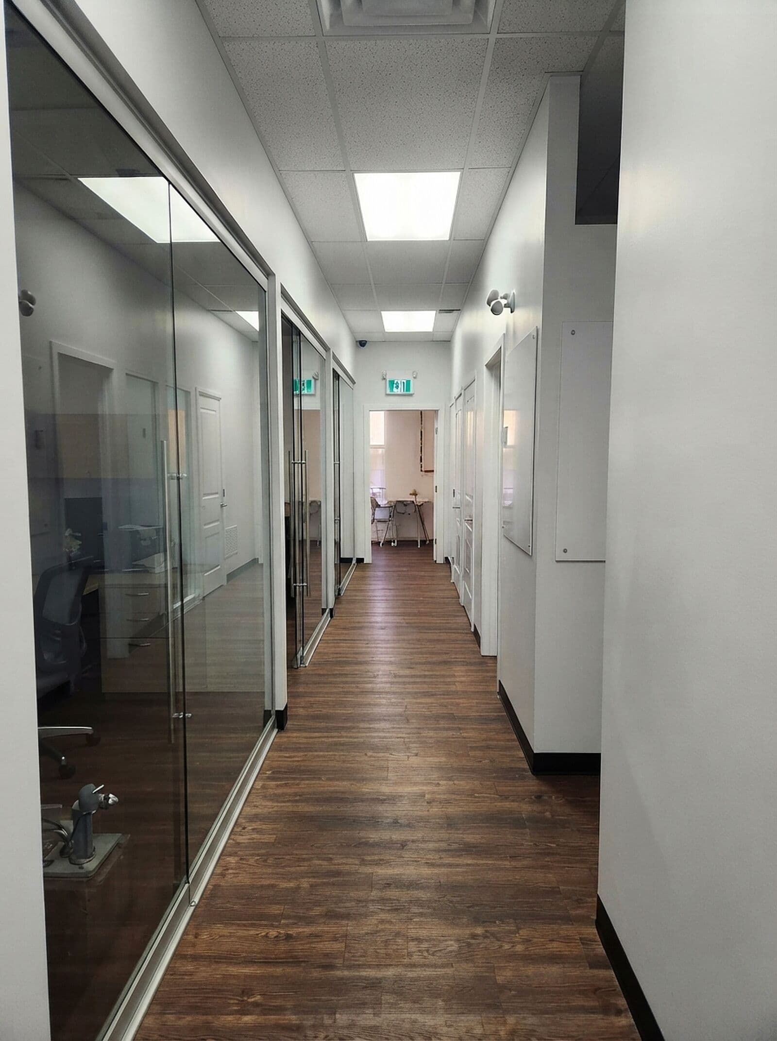 Hallway leading to the glass-walled treatment rooms at Riverside Landing Dental in St. Albert